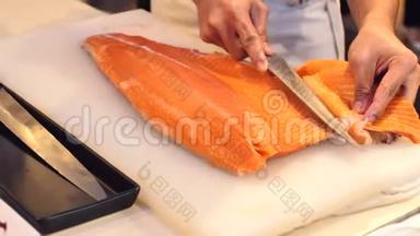 <strong>寿司厨师</strong>的特写展示了一个`的能力切片新鲜鲑鱼在<strong>寿司</strong>吧。