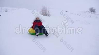 女孩在冬天滑雪从高山雪橇和充气雪管。 少女在冬季公园玩耍