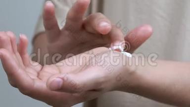 一个女人的特写`她的手腕上的手测试霜。 她把一滴滴在手腕上，把它揉进皮肤里。