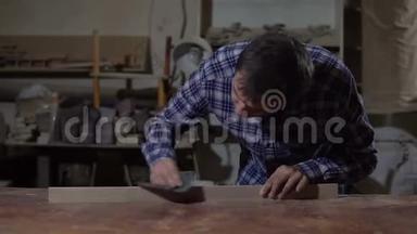 木工在桌面上用砂纸打磨木板.. 木工车间的工作