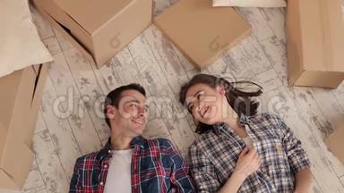 幸福的一对夫妇躺在地上，手里拿着未<strong>打包</strong>的<strong>盒</strong>子。