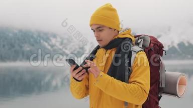 徒步旅行者使用智能手机拍摄冬季自然的照片。 游客崇尚自然，制作照片.. 年轻人
