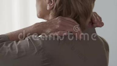 老年妇女按摩脖子和肩膀，感到疼痛和不适