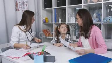 母女俩在诊所<strong>看病</strong>。 女医生和母亲和孩子谈话，给她一点