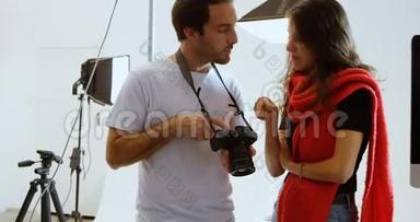 男子摄影师向女子模特展示数码相机4k的照片