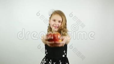一个卷曲的女孩拿着苹果对着相机。 一个漂亮的孩子提供一个<strong>大红</strong>苹果