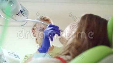 女牙医治疗病人牙齿。 戴护目镜的金发医生