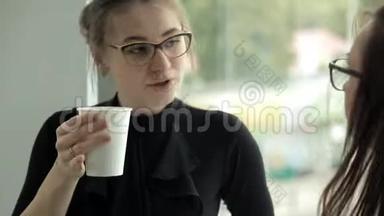 两个在银行工作的女商人在窗口喝咖啡，午餐时交流。 工作，咖啡，交流