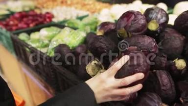 年轻女子在商店<strong>货架</strong>上选择红色卷心菜。 Ð一个有魅力的年轻女人手里拿着一种<strong>蔬菜</strong>。