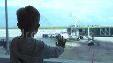 小男孩在机场<strong>候机</strong>室等飞机时看着窗。 小男孩从飞机上