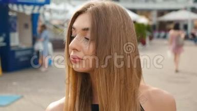 脸浅棕色头发的年轻女人看着镜头近距离。 城市街头背景的肖像美女