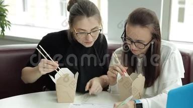 两个年轻女孩坐在咖啡馆里，吃着<strong>中国</strong>面条，计划着商业<strong>发展</strong>
