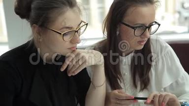 两个女孩坐在咖啡馆里，讨论商业想法，给她们带着午餐面条