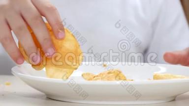 白色盘子里有薯片，宝宝手里拿着薯片从盘子里拿出来.. 特写镜头。