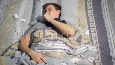 感冒和流鼻涕的病人躺在家里的沙发上用纸巾擦鼻涕