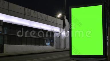 时光流逝。 有绿色屏幕的广告牌，位于一条繁忙的街道上。 汽车在晚上移动。
