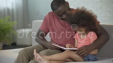 可爱的父亲看着他的小卷发女儿学习阅读