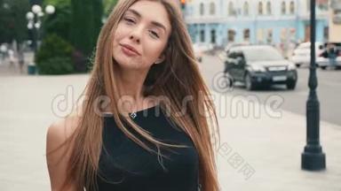 脸浅棕色头发的年轻女人看着相机的稳定镜头。 城市街道上的肖像美女
