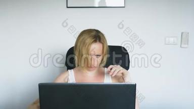 一个女人用她的笔记本电脑坐在桌子旁，愤怒和恼怒。 人类的情感。 网瘾。