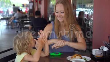 年轻女子和儿子在咖啡馆里用洗手液