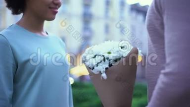 可爱的男人向漂亮的女朋友献花，拥抱夏天的约会城市