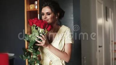 美丽而华丽的女人穿着浴袍闻着<strong>一束红玫瑰</strong>。