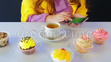 那个在桌旁的咖啡馆里吃蛋糕的女孩在智能手机里翻阅新闻