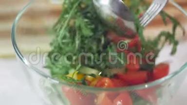 一个女人用玻璃碗折叠蔬菜沙拉原料的手的特写