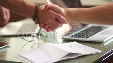 两个商人的亲密握手。 男人互相握手。 商业概念，交易，桌上的笔记本电脑