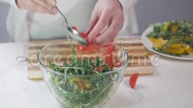 一个女人用<strong>玻璃碗</strong>折叠<strong>蔬菜</strong>沙拉原料的手的特写