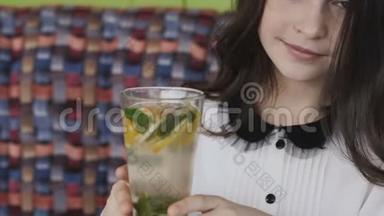 美丽的女孩在咖啡馆里津津有味地喝着柠檬水