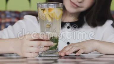 美丽的女孩在咖啡馆里津津有味地喝着柠檬水