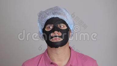 男人用一个恢复青春活力的黑色组织面膜洗脸，吓得眼睛向两边眨