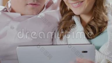 一对夫妇看着平板电脑，放大屏幕，选择物品来装饰房子