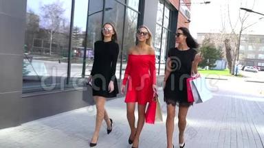 三个可爱的年轻女人走在街上，享受他们的购物日。 穿着<strong>漂亮衣服</strong>的年轻女子