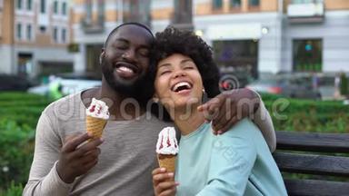 快乐的男女朋友在长凳上笑，和冰淇淋的浪漫约会