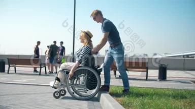 一个男人推着轮椅。 男人帮助坐轮椅的女人