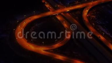 在充满汽车和卡车的夜晚，一个大的照明道路交叉口的空中景观。