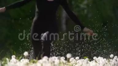 快乐的年轻女子穿过飞舞的绒毛跑到蒲公英的草地上