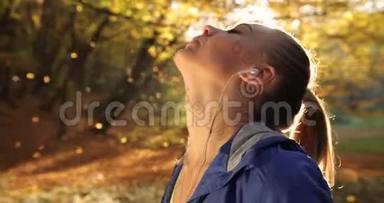 公园里的女跑步者。 女人喜欢落叶，站在清晨的阳光下，休息一下