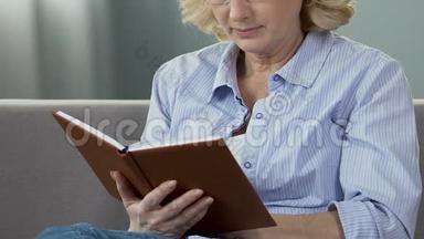 退休妇女坐在沙发上看书，热衷于读书，闲暇时间
