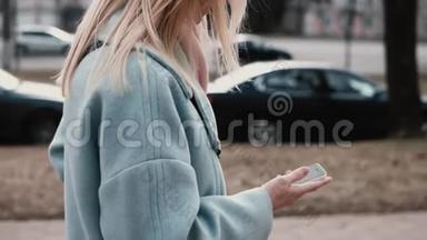 穿着蓝色外套的慢动作金发女人发短信。 侧视。 女孩在发信息。 生活方式。 高的生活节奏..