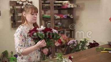 女孩正在准备一束鲜花和绿叶，准备在一家花店里交易