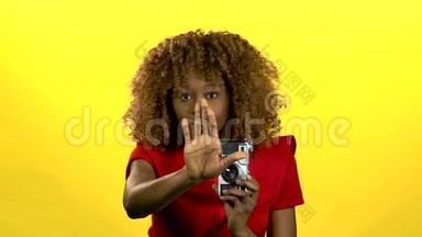 美国黑人<strong>摄影</strong>师手里拿着相机，竖起<strong>大拇指</strong>。 黄色背景。 慢动作