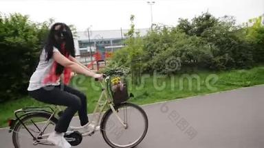 骑自行车的快乐年轻女人的肖像。 她的自行车篮子里有花和一个包。 她喜欢<strong>这次</strong>旅行。