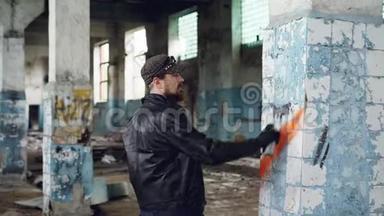 胡子涂鸦艺术家正在用气溶胶涂料在旧废弃建筑的柱子上作画。 现代青年亚<strong>文化</strong>