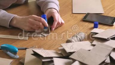 女人用牛皮纸做了一个纸袋，用来做日历。 双手特写.. 把纸粘上。