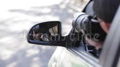 年轻的私家侦探坐在车里，用数码相机拍摄侧镜的倒影