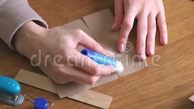 女人用牛皮纸做纸袋。 双手特写.. 把纸粘上。