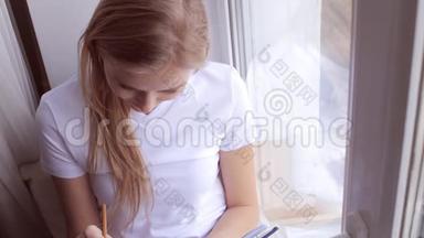 年轻女子坐在窗台上写日记或日记